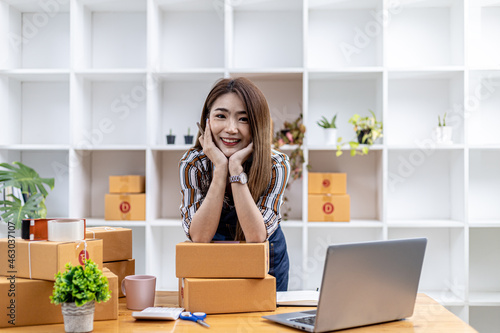 A beautiful Asian business owner opens an online store, packaging products with parcel boxes, sending goods through a private transport company, a concept image of a woman opening an online business.