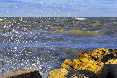 Schizzi d'acqua di un' onda che si infrange sulla scogliera photo