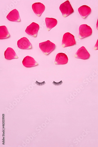 Creative woman face made of eyelashes and rose petals hair on the pink background. Minimal beauty concept. Makeup creative concept. Flat lay.