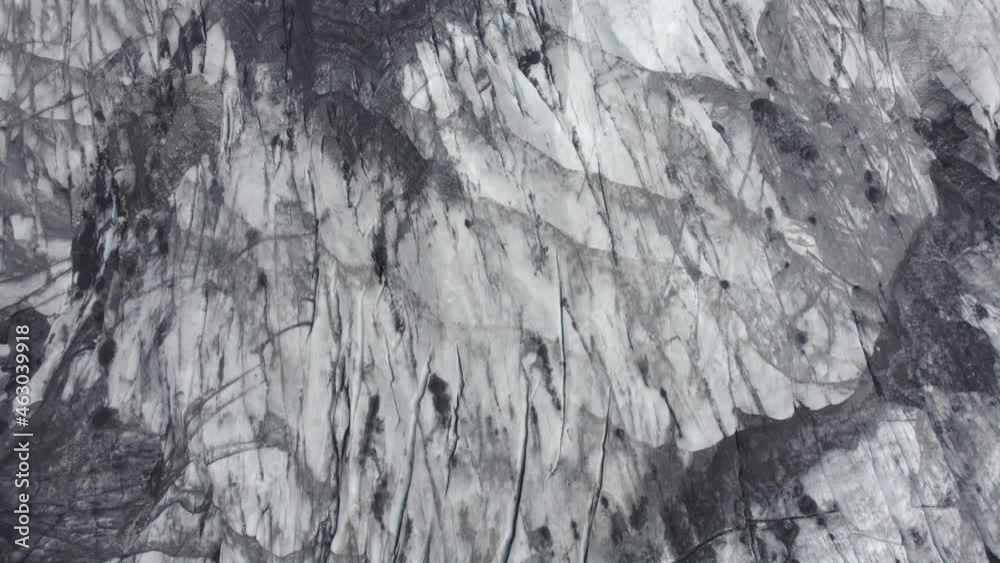 Aerial view above a ashy, darkened glacier surface, in Iceland - birds eye, drone shot