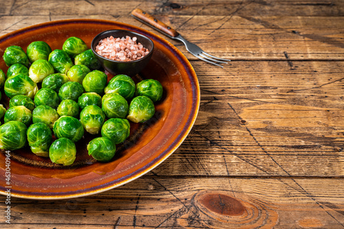 Cooked Brussels green sprouts cabbage in a rustic plate with salt. wooden background. Top view. Copy space
