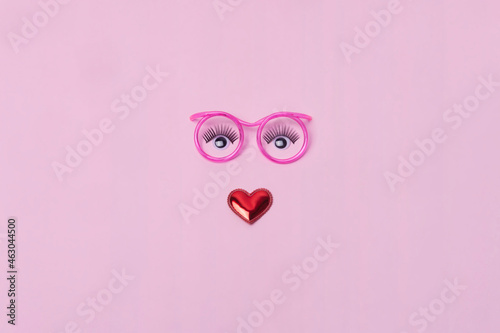 Creative makeup concept with  pink glasses, eyelashes and heart on the pink background. Makeup creative concept. Flat lay.