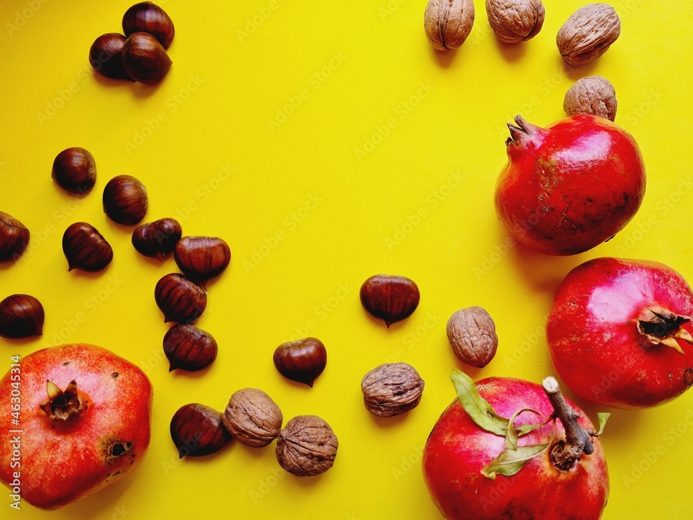 yellow background with autumn products, pomegranates chestnuts nuts yellow background with autumn products, pomegranates chestnuts nuts