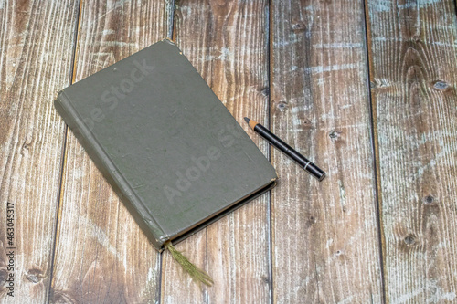 old heavily used closed sketchbook and pencil on a worn brown colored wooden surface
