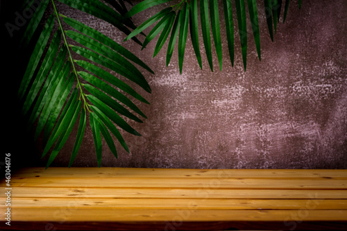 wooden table for show product display and presentation, palm leaves and dark rugged background, copy space, selective focus.