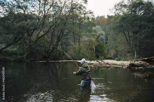 Fly fisherman casting with artificial flies on the river during autumn.