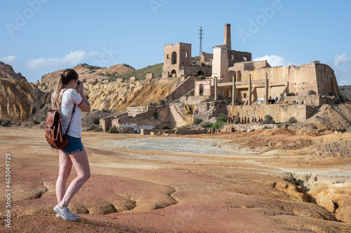 Young and pretty girl with FPP2 mask taking pictures with an analog camera in the abandoned Mazarron mines photo