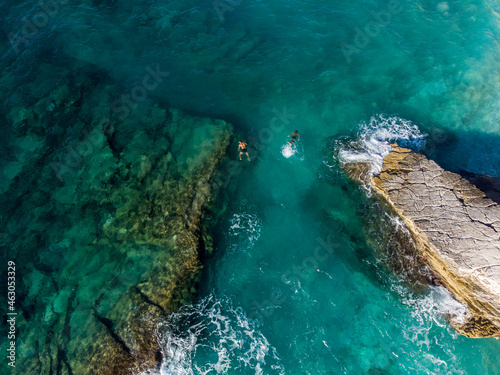 Aerial drone view of swimmers in the sea at summer. Tourists diving and swimming in the water. Transparent sea water in bay. © Ajdin Kamber