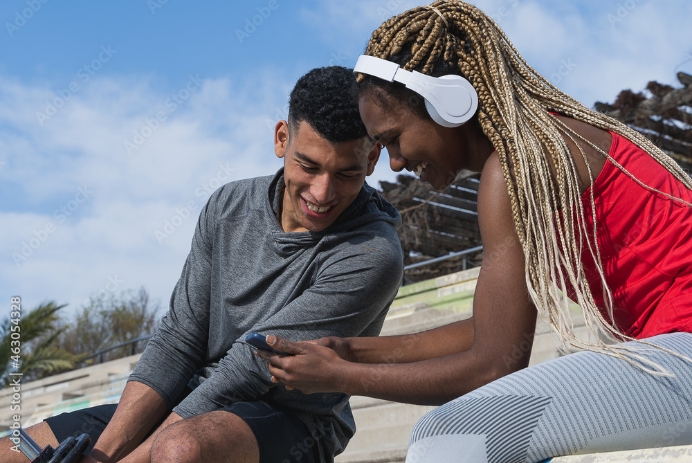 Fototapeta premium Interracial friends having fun with the cell phone after workout