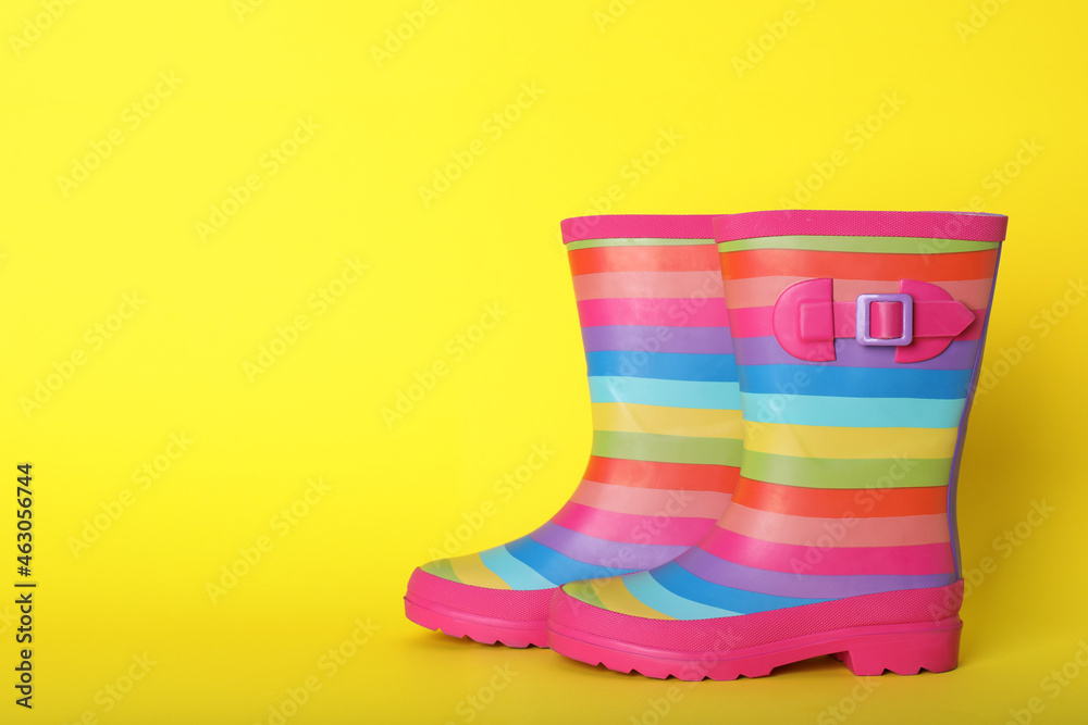 Pair of striped rubber boots on yellow background. Space for text Pair of striped rubber boots on yellow background. Space for text
