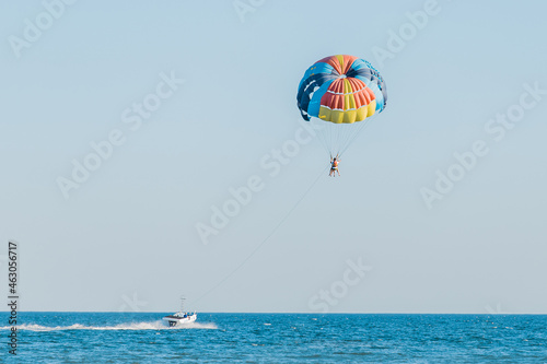 Ukraine, Iron Port - August 31, 2020: Extreme sports and exciting rest activity. Vacationing tourists fly on a parashute over the sea against the background of blue sky and horizon line