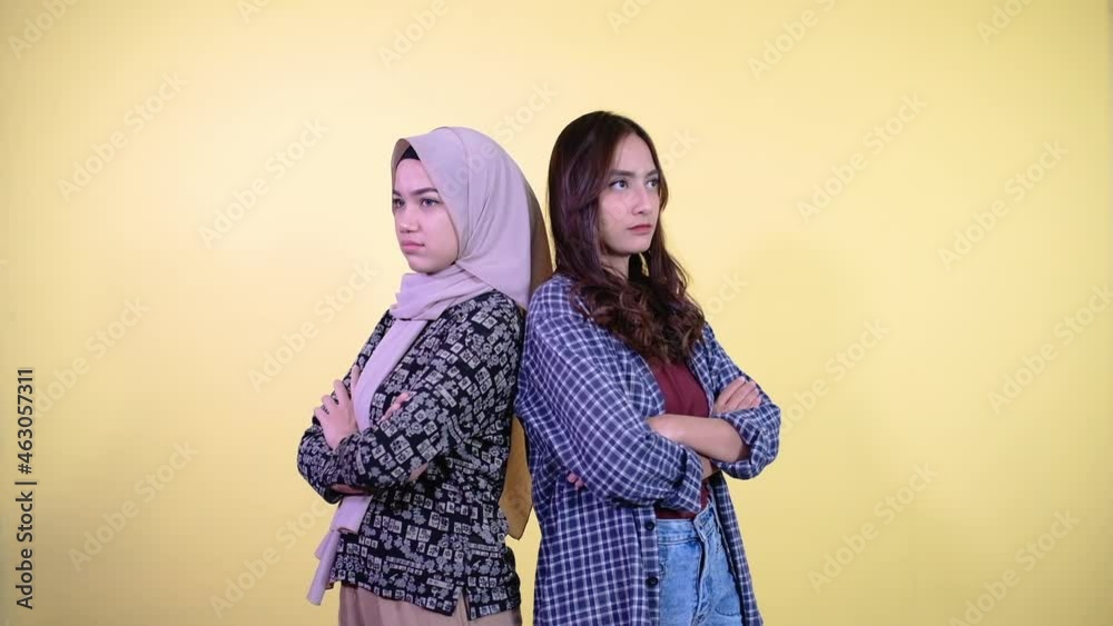 two sad asian girls standing back to back and crossed hands with copyspace two sad asian girls standing back to back and crossed hands with copyspace