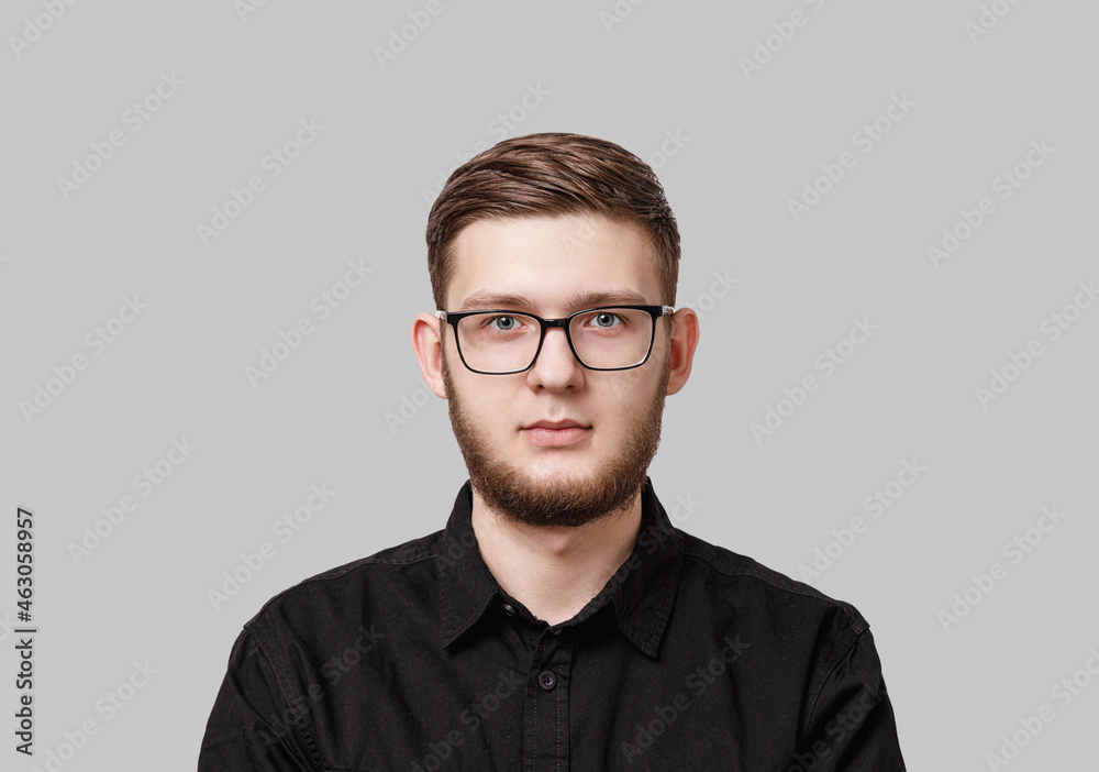 Young serious man with stylish neat beard, wearing a black shirt and in glasses Young serious man with stylish neat beard, wearing a black shirt and in glasses