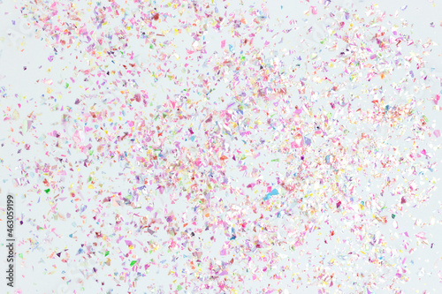 Holographic colorful confetti on a blue pastel background. Multicolored backdrop.
