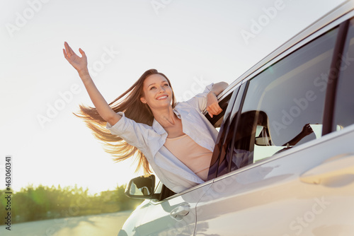 Photo portrait smiling woman riding in car with flying on wind hair waving hand meeting © deagreez