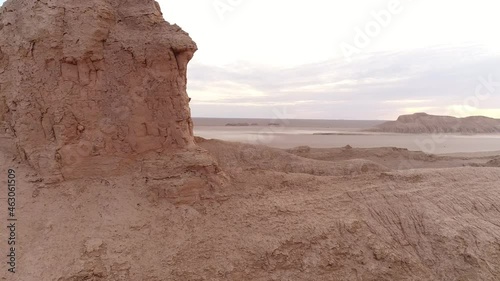 dolly shot from the formation of sandstones in dasht e lut desert at the morning with cloudy sky and flat ground in background, aerial shot the formation of kalut in shahdad desert, iran photo