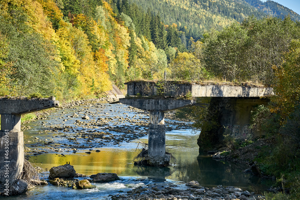 Ruined bridge on a mountain river. Ruins of the columns of the bridge in the Carpathians.