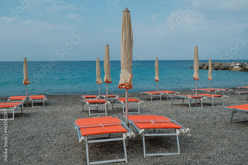 Φωτογραφία Orange beach chairs and umbrellas on the pebble beach across beautiful blue seacoast till the horizon
