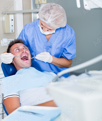 Professional dentist examining and performing treatment to young man