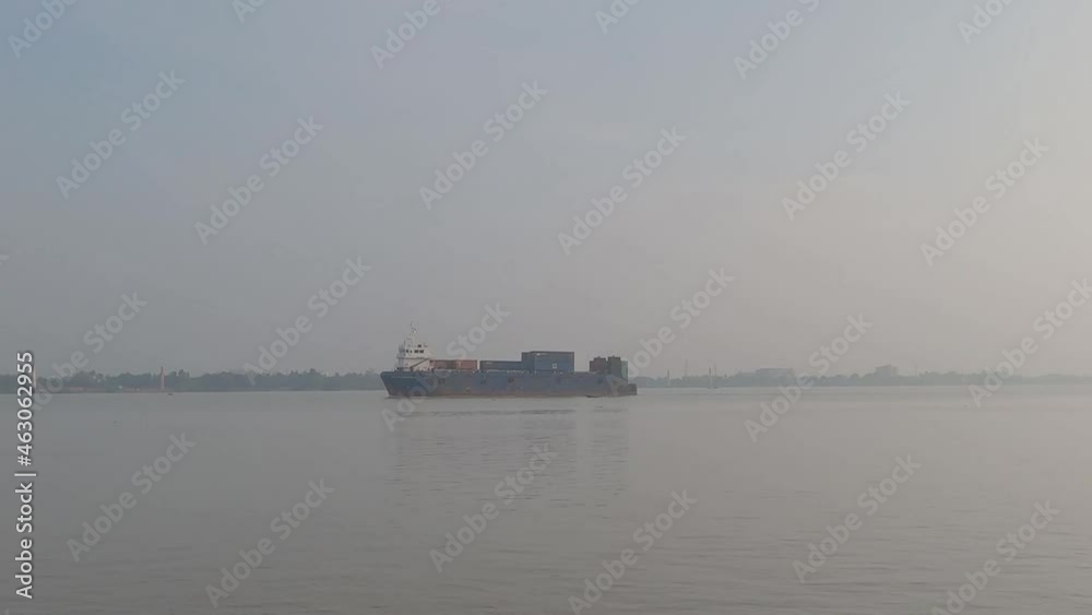Container ship passing on a River Horizon during sunset against clear sky background. Container ship passing on a River Horizon during sunset against clear sky background.
