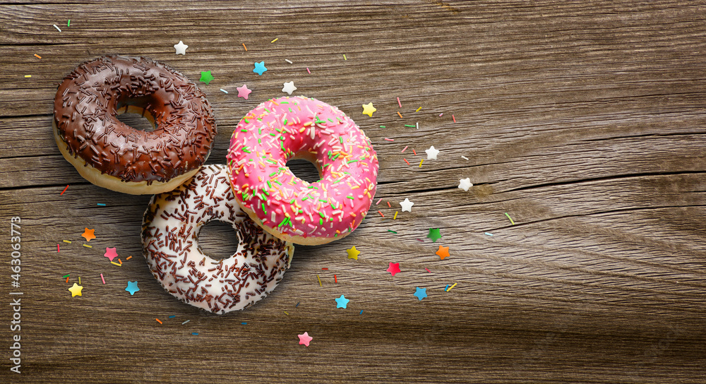 Assorted donuts glazed with sprinkles on wooden table.