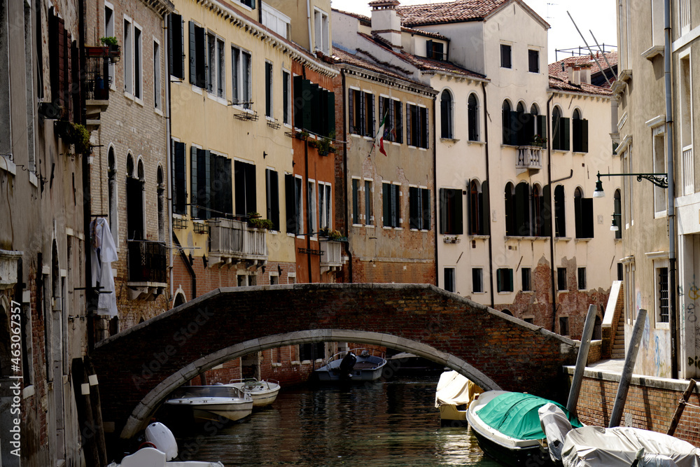 Old canal street with boats and bridge in Venice, Italy