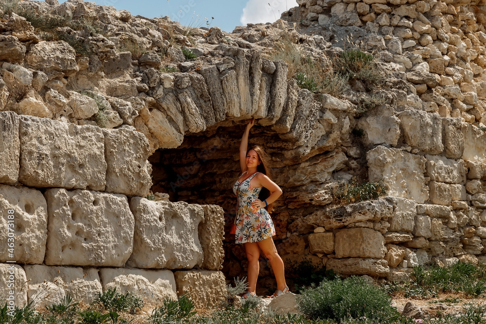 A girl in a dress goes to the ancient ruins of the fortress. Tourism in Crimea. Travel around Europe.