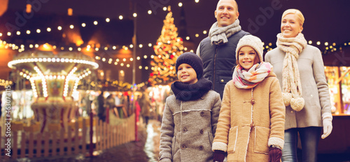 winter holidays, leisure and people concept - happy family over evening christmas market or amusement park background