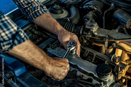 Repairman's male hands with a wrench. Vehicle fitter inspecting used car engine