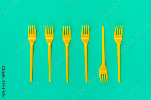 Yellow disposable forks lying on the blue background