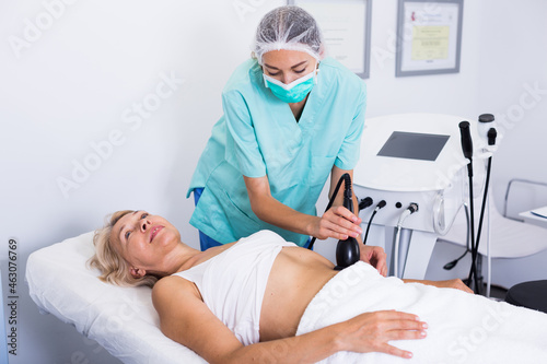 Woman receiving innovative procedure of cryoliposuction in clinic of esthetic cosmetology