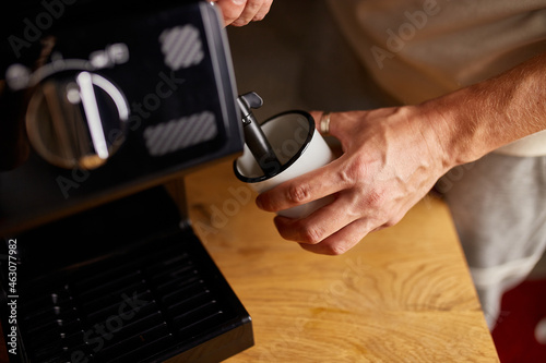 An Anonymous Barista Making a Cappuccino in a Coffee Chop, Male barista hand making espresso from ground coffee maker at modern cafe