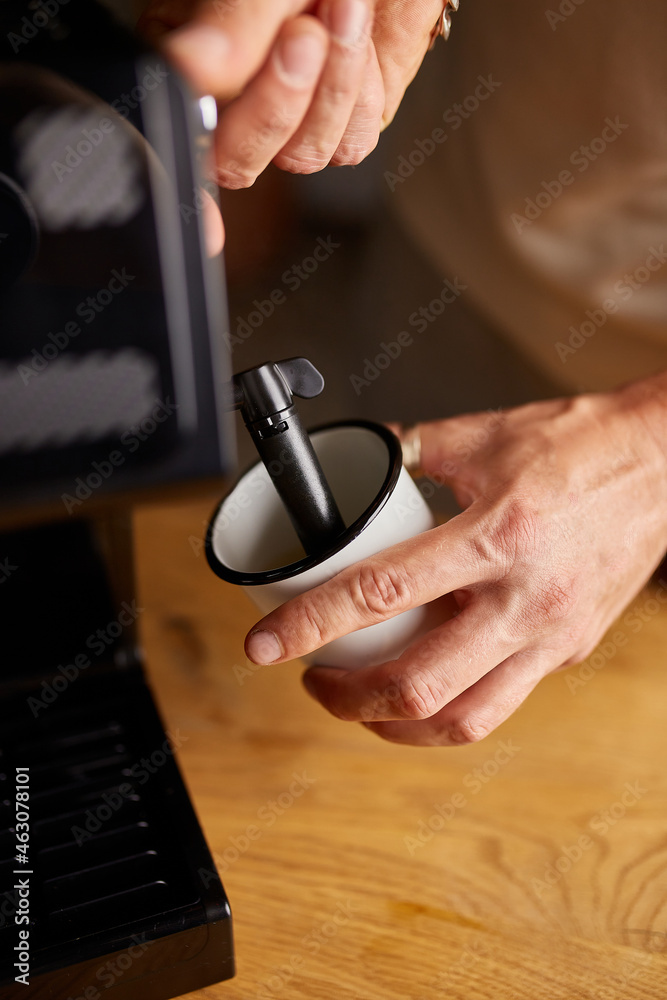 An Anonymous Barista Making a Cappuccino in a Coffee Chop, Male barista hand making espresso from ground coffee maker at modern cafe An Anonymous Barista Making a Cappuccino in a Coffee Chop, Male barista hand making espresso from ground coffee maker at modern cafe