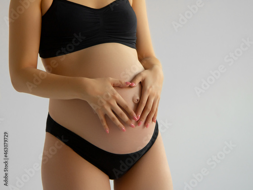 Image of pregnant woman touching her big belly. Close up. Motherhood, pregnancy, people and expectation concept. Pregnant woman expecting baby . Beauty woman with on white background