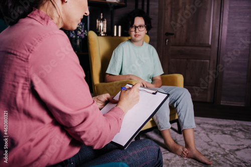 close-up of a female psychologist sitting in a chair and making a recording of the reception of a teenage girl