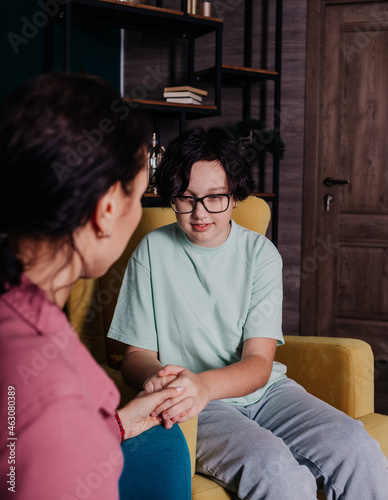 a Caucasian teenage girl is sitting in a chair in a room at a reception with a female psychologist