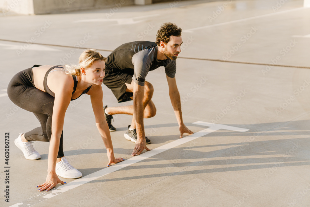 Young runners doing exercise while working out together on parking