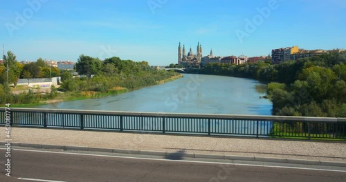 View Of Ebro River And Cathedral Basilica Of Our Lady Of The Pillar From Almozara Bridge In Zaragoza, Spain With Cars Passing In Foreground. wide slider photo