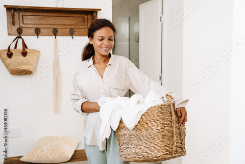 фотографія Black woman smiling while holding basket with clothes