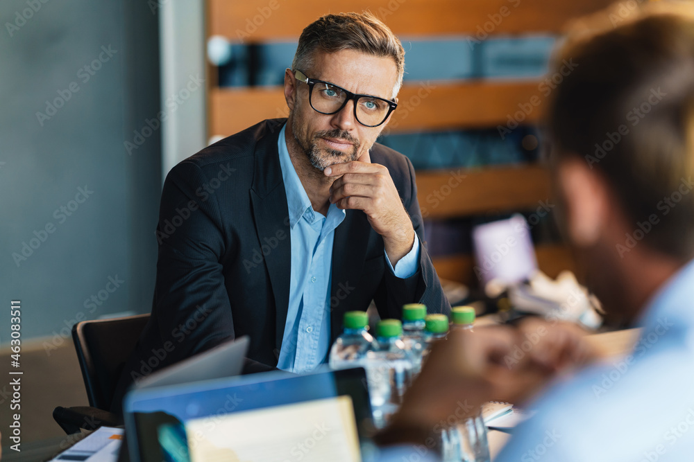 Adult white men discussing business project during meeting in office