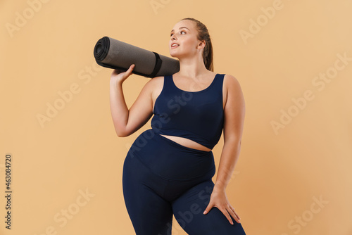 Young woman wearing sport suit smiling while posing with fitness mat © Drobot Dean