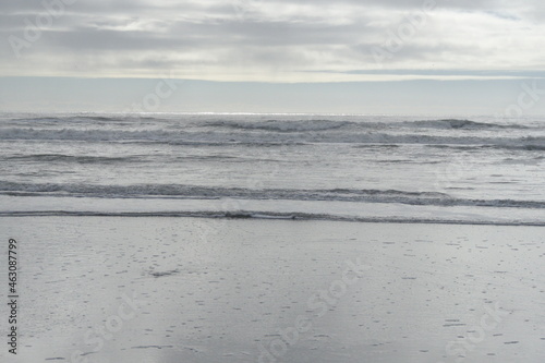 Rolling Waves on Cloudy Horizon with Wet Sandy Beach