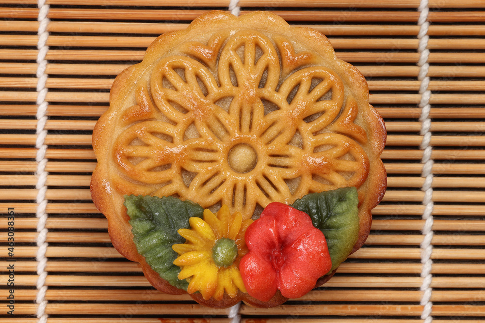 Colorful flower decorated mooncake Chinese mid autumn festival on bamboo food mat background