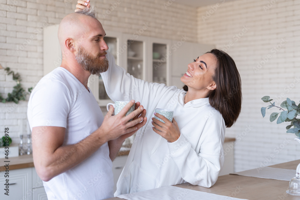Young couple husband with wife at home in the kitchen, happy smile laugh, drink coffee in the morning, chat, discuss plans for the day Young couple husband with wife at home in the kitchen, happy smile laugh, drink coffee in the morning, chat, discuss plans for the day