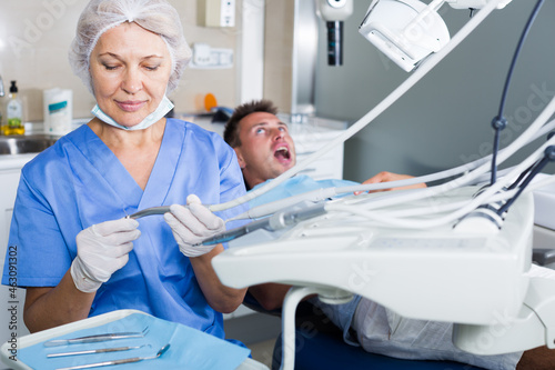 Portrait of professional dentist in dental clinic with patient behind