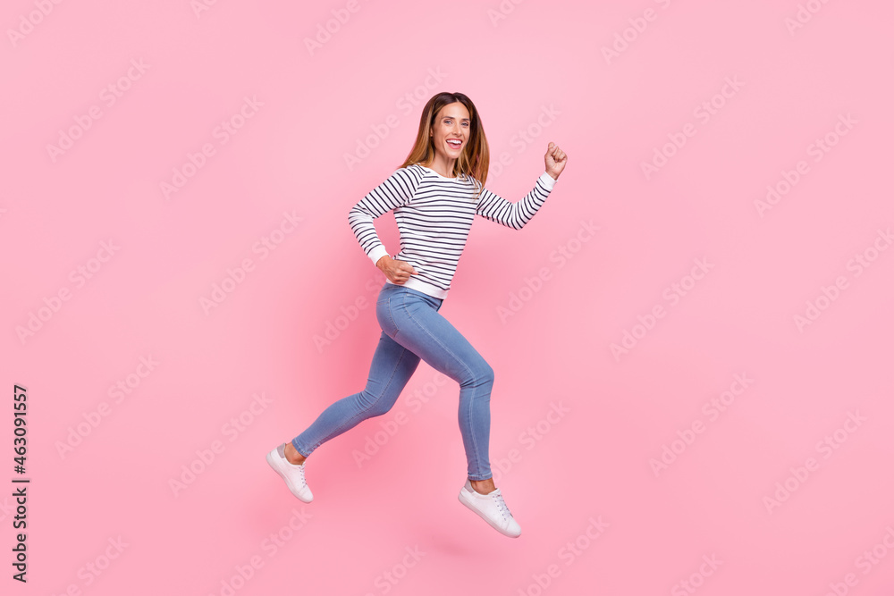 Full lenght profile photo of mature nice brown hairdo lady run wear shirt jeans sneakers isolated on pink background