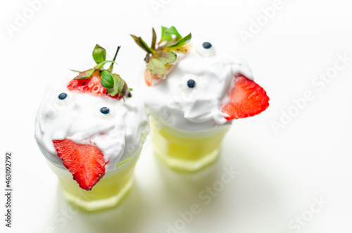 Egg liqueur in shot glass decorated with fluffy whipped cream and pieces of strawberry, served in funny way photo