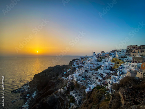 panoramic view of Oia village with traditional white architecture and windmills in Santorini island in Aegean sea at sunset, travel background, Santorini, Thera, Greece