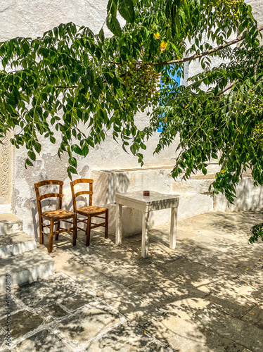 two chairs and a table on a shaded terrace under an Acacia tree
