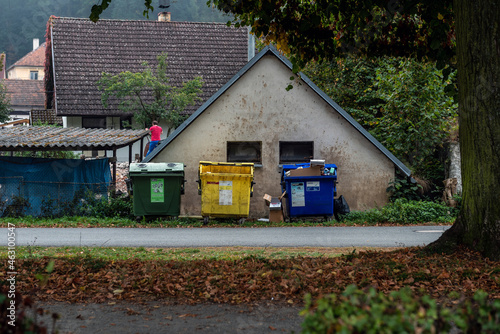 colorful waste sorting containers in front of a village house